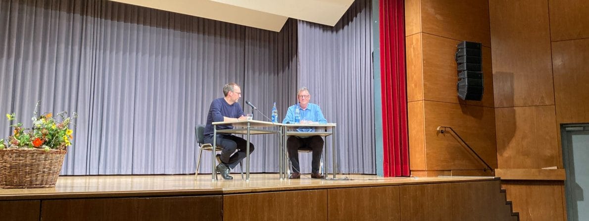 Lesen an dem Tisch, an dem man vor fast 30 Jahren auch sein Abitur gemacht hat: Michael Ebert (links) mit Moderator Christoph Plum in der Aula des Schramberger Gymnasiums (Foto: Tischer)